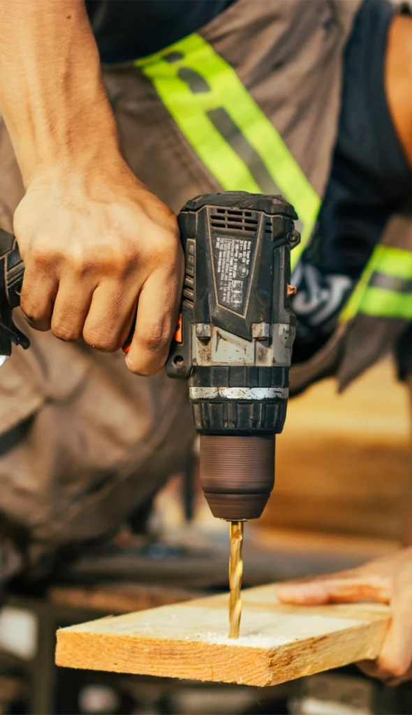 Undistinguishable man using a cordless, battery operated drill