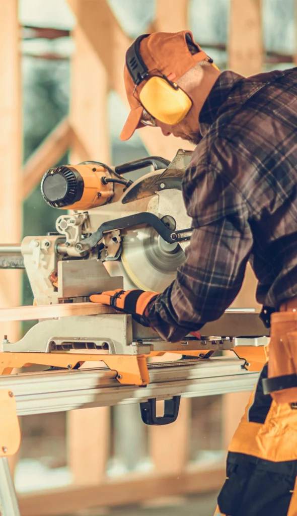 Undistinguishable older man wearing ear protection using a mitre saw on a stand